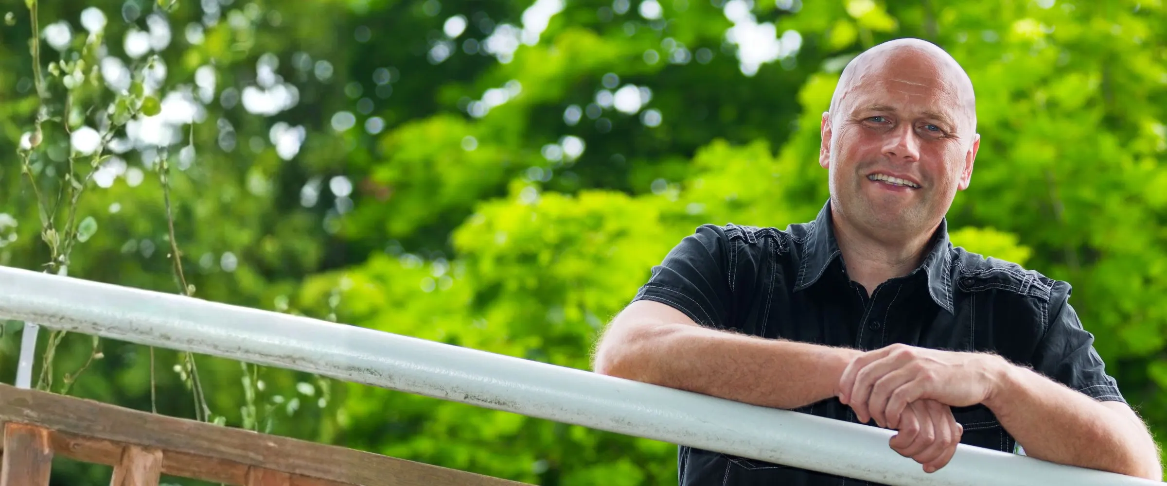 Miroslav Kubásek opřený o zábradlí, v pozadí zeleň